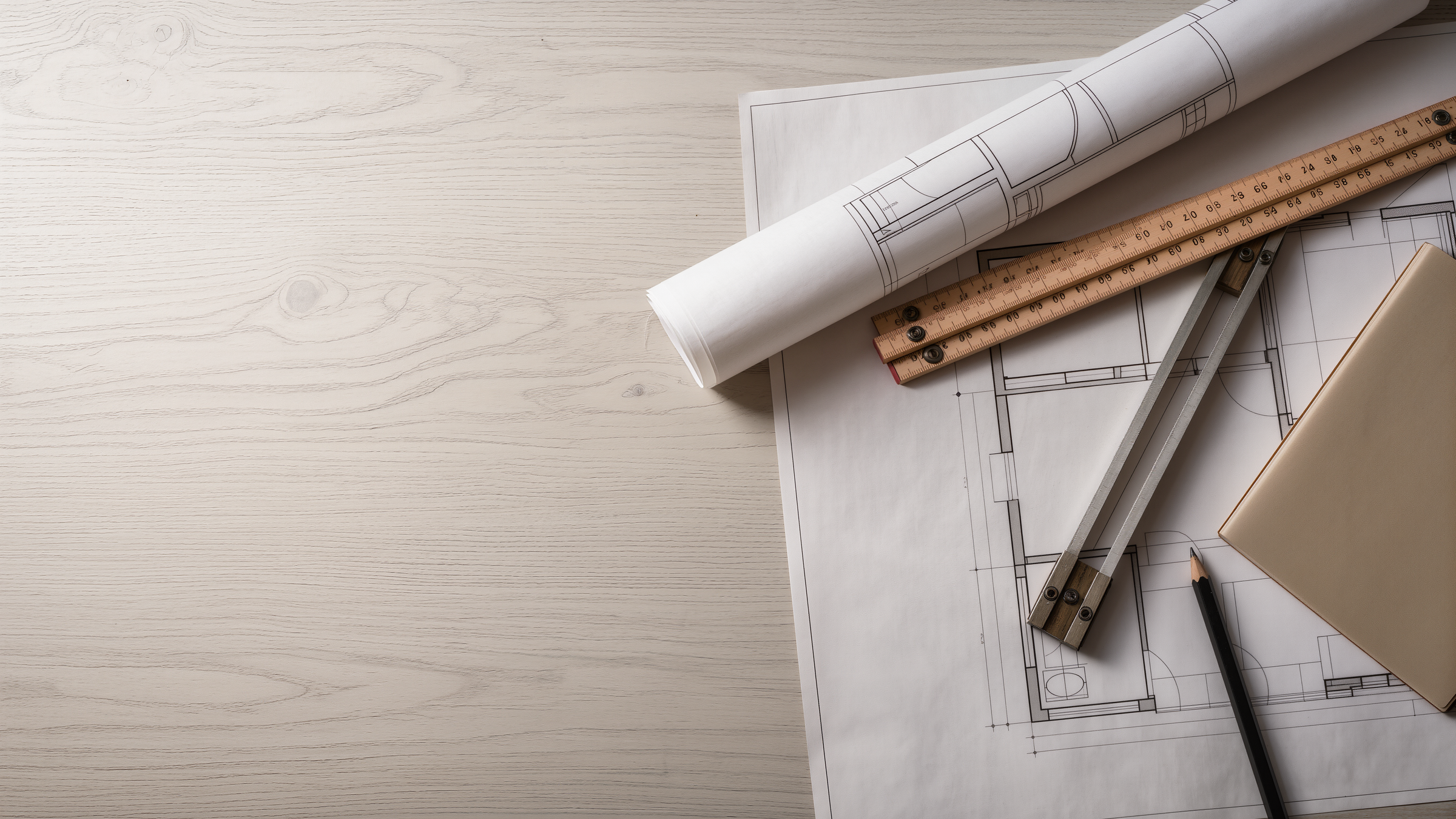 Bauplan, Massstab und Zirkel auf einem hellen Tisch